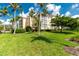 Exterior view of a multi-story building with tropical trees and green grass at 255 W End Dr # 4210, Punta Gorda, FL 33950