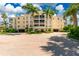 Beautiful condo building with lush landscaping, circle drive, and towering palm trees on a sunny day at 255 W End Dr # 4210, Punta Gorda, FL 33950