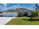 Three-car garage, light beige exterior, and lush landscaping at 269 Mariner Ln, Rotonda West, FL 33947