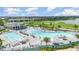 Aerial view of community pools, lounge chairs, and golf course in background at 43996 Boardwalk Loop # 1411, Punta Gorda, FL 33982