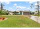 Single-story home with a landscaped lawn, attached garage, and teal front door at 5273 Crestline Ter, Port Charlotte, FL 33981