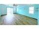 Bright living room featuring light blue walls, wood flooring, and sliding glass doors at 6642 Acacia Ct, North Port, FL 34287