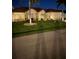 Night view of a single-story home with a tile roof, landscaping, and a paved driveway at 720 Bimini Ln, Punta Gorda, FL 33950