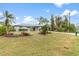 Landscaped front yard of one-story house featuring palm trees and shrubs at 1264 Shadow Ln, North Port, FL 34286