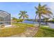 Landscaped canal-front yard with a walkway leading to a dock at 17456 Foremost Ln, Port Charlotte, FL 33948