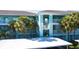 Building exterior, featuring light teal paint, palm trees, and covered parking at 19375 Water Oak Dr # 203, Port Charlotte, FL 33948