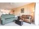 Living room with green and brown sofas, and access to the balcony at 19375 Water Oak Dr # 203, Port Charlotte, FL 33948