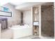 Spa-like bathroom featuring a corner bathtub, walk-in shower, and tile surround at 25188 Marion Ave # 12, Punta Gorda, FL 33950