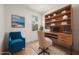 Cozy office space with custom wood shelving, natural light, and a comfortable blue armchair at 27066 Sumatra Dr, Punta Gorda, FL 33955