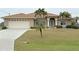 Tan house with brown roof, palm trees, and a grassy yard at 273 Mark Twain Ln, Rotonda West, FL 33947