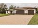 Three-car garage, paver driveway, and landscaped front yard at 3495 Levee St, North Port, FL 34288