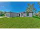 Newly built home showcasing a gray exterior, attached garage, and a lush green lawn at 5049 Birdsong St, North Port, FL 34291