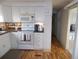 White kitchen with wood flooring, microwave, range, and view of hallway at 5232 Palena Blvd, North Port, FL 34287