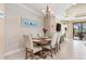 Dining room with light wood table and six beige chairs, wood-paneled wall at 1259 Backspin Dr, Englewood, FL 34223