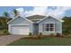 Single-story home with light blue exterior, white garage door, and landscaping at 1422 Powell Valley Dr, Port Charlotte, FL 33953