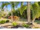 Relaxing garden area with a metal bench, palm trees, and colorful plants at 1785 Nagorsky Ave, North Port, FL 34288