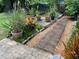 A brick pathway leads through a garden with potted plants and a deck at 18085 Wintergarden Ave, Port Charlotte, FL 33948