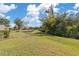 Scenic backyard view with lush green lawn and mature trees by a calm canal at 2860 Arugula Dr, North Port, FL 34289