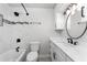 Modern bathroom with white cabinets, marble tile, and a round mirror at 121 Cambridge Nw Dr, Port Charlotte, FL 33952