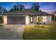 Single story house at dusk with dark brown garage door at 509 Sunset N Rd, Rotonda West, FL 33947