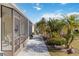 Screened patio, lush landscaping, and a paved walkway leading to the backyard at 6796 Gasparilla Pines Blvd # 77, Englewood, FL 34224