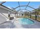 Screened-in pool with tile surround and partially-covered lanai in backyard at 1230 Gantry Rd, North Port, FL 34288