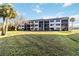 Exterior view of the building with a large lawn, palm trees and blue skies at 1999 Kings Hwy # 16B, Punta Gorda, FL 33980