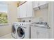 Bright laundry room with a front-load washer/dryer and storage cabinets at 2580 Brazilia Ct, Punta Gorda, FL 33950