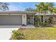 Front entrance with gray door and landscaping at 3189 Tally Ho Rd, North Port, FL 34291