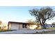 Tan single-story house with a white garage door and large tree in front at 4200 Kilpatrick St, Port Charlotte, FL 33948