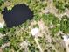 Aerial view shows the house on a large lot with a pond and lush vegetation at 1136 Davis Ln, Englewood, FL 34224