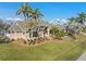 Stunning exterior view of a single-story home with lush landscaping and mature palm trees against a blue sky at 1701 Casey Key Dr, Punta Gorda, FL 33950