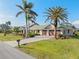 Lovely home exterior with a three-car garage, a lush green lawn, and a beautifully paved driveway lined with mature palm trees at 1701 Casey Key Dr, Punta Gorda, FL 33950