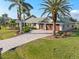 Charming waterfront home with a three-car garage, lush landscaping, and a paved driveway surrounded by mature palm trees at 1701 Casey Key Dr, Punta Gorda, FL 33950