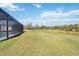 Spacious backyard view with pool enclosure, wetland vegetation, and trees at 2154 Azure Rd, North Port, FL 34286