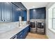 Bright laundry room with blue cabinetry, stainless steel washer and dryer, and sleek countertops at 2154 Azure Rd, North Port, FL 34286