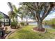 Beautiful backyard landscaping with large shade tree, tropical plants, and canal view at 3507 Marsala Ct, Punta Gorda, FL 33950