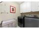 Laundry room with front loading washer and dryer, upper cabinets, and neutral color palette at 3507 Marsala Ct, Punta Gorda, FL 33950