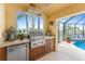 Outdoor kitchen featuring built-in grill, stainless steel fridge, counterspace, and view of pool and waterway at 3507 Marsala Ct, Punta Gorda, FL 33950