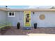 Front entry with a bright yellow door, welcoming patio, and potted plants at 351 S Mccall Rd, Englewood, FL 34223