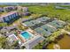 Beautiful aerial view of community amenities: pool and tennis courts with water views at 5220 Landings Blvd # 104, Sarasota, FL 34231