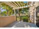 Private patio with a pergola overlooking a serene pond with lush greenery and mature trees at 5220 Landings Blvd # 104, Sarasota, FL 34231