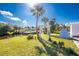 Green backyard featuring palm trees, a river/canal view with a covered boat dock, and a modern white arbor at 1052 Eppinger Dr, Port Charlotte, FL 33953