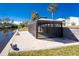 Canal-front backyard featuring a covered patio, brick pavers, and lush tropical landscaping at 1052 Eppinger Dr, Port Charlotte, FL 33953