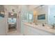 Bathroom featuring dual sinks, white cabinetry, and a tiled floor next to bedroom entrance at 1407 Red Oak Ln, Port Charlotte, FL 33948