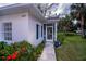 Home's entry with a walkway, screened-in porch, and flowering landscaping on a sunny day at 1407 Red Oak Ln, Port Charlotte, FL 33948