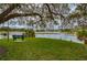 Tranquil lake view with a peaceful bench under a shady tree, inviting relaxation at 1407 Red Oak Ln, Port Charlotte, FL 33948