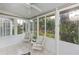 Bright sunroom featuring tile floors, a ceiling fan, large windows, and views of the lush outdoor landscape at 1407 Red Oak Ln, Port Charlotte, FL 33948