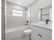 Bright bathroom featuring a tub with shower, window, gray tiling and vanity with black modern fixtures at 16031 Hesta Misty Ct, Punta Gorda, FL 33955