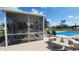 Outdoor poolside seating area in a screened in enclosure with a partial view of the pool on a sunny day at 181 Coconut St, Punta Gorda, FL 33980